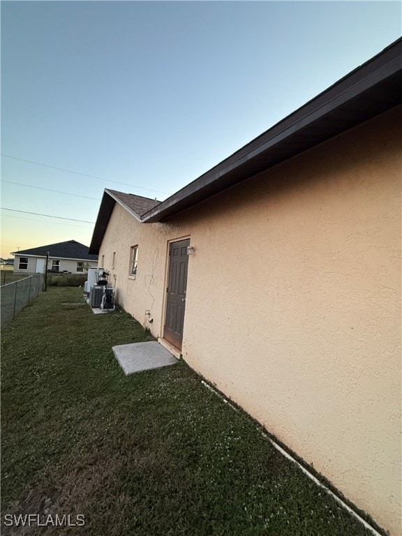 property exterior at dusk featuring a yard