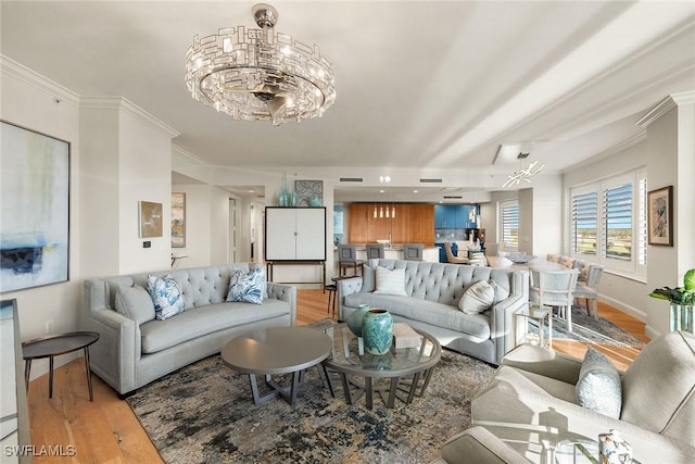 living room with light hardwood / wood-style floors, an inviting chandelier, and ornamental molding