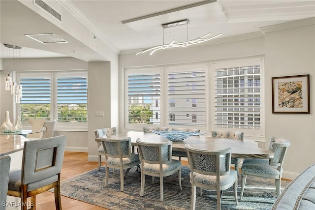 dining space with ornamental molding, light hardwood / wood-style floors, and a healthy amount of sunlight