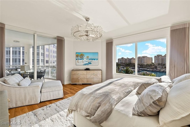 bedroom featuring access to exterior, wood-type flooring, and an inviting chandelier