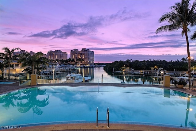 pool at dusk featuring a water view