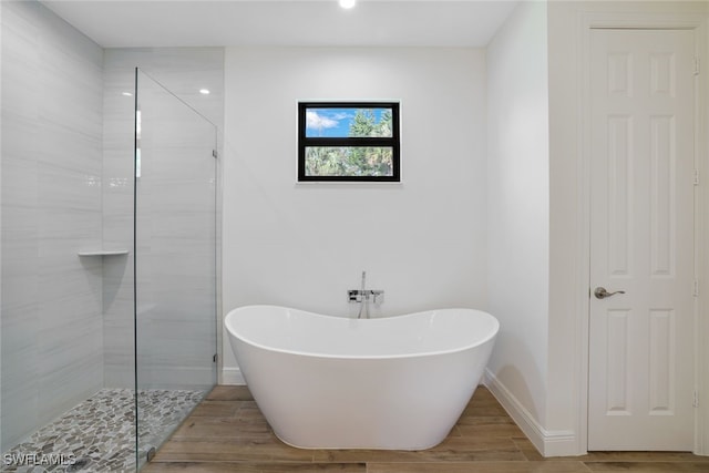 bathroom with a freestanding bath, a tile shower, and wood finished floors