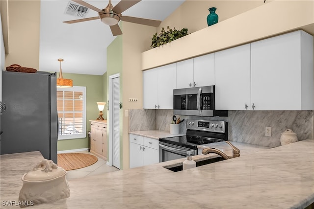 kitchen featuring appliances with stainless steel finishes, sink, light tile patterned floors, white cabinets, and hanging light fixtures