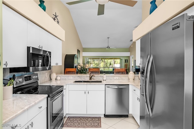 kitchen with sink, vaulted ceiling, light stone countertops, white cabinetry, and stainless steel appliances