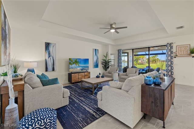 tiled living room featuring a raised ceiling and ceiling fan