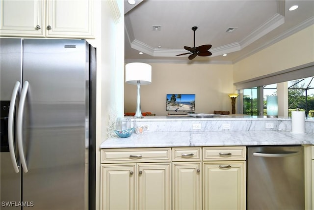 kitchen with a tray ceiling, ceiling fan, crown molding, and stainless steel appliances