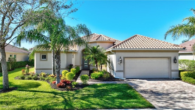 mediterranean / spanish-style house featuring a garage and a front lawn