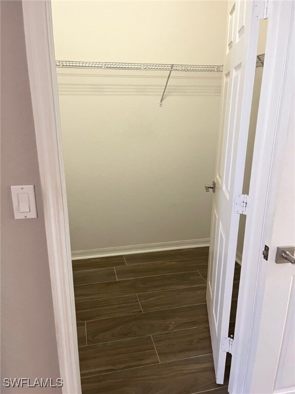 walk in closet with dark hardwood / wood-style floors