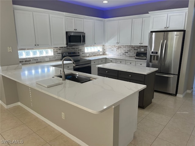 kitchen featuring white cabinets, sink, light tile patterned floors, a kitchen island, and stainless steel appliances