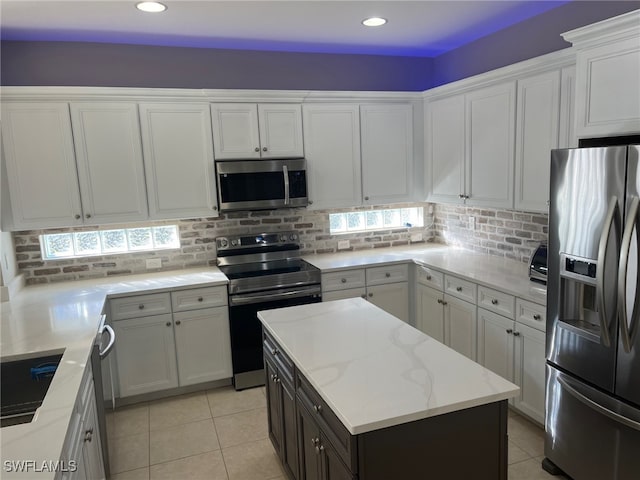 kitchen with white cabinets, stainless steel appliances, a kitchen island, and tasteful backsplash