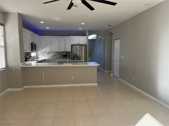 kitchen with white cabinetry, ceiling fan, stainless steel appliances, kitchen peninsula, and decorative backsplash