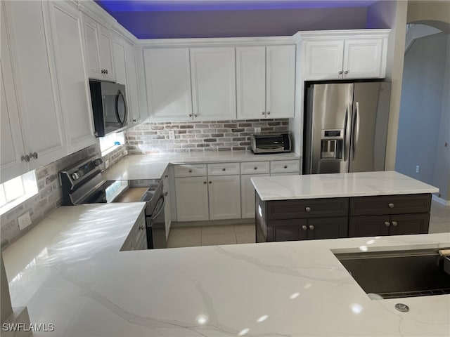 kitchen featuring backsplash, stainless steel appliances, and white cabinetry