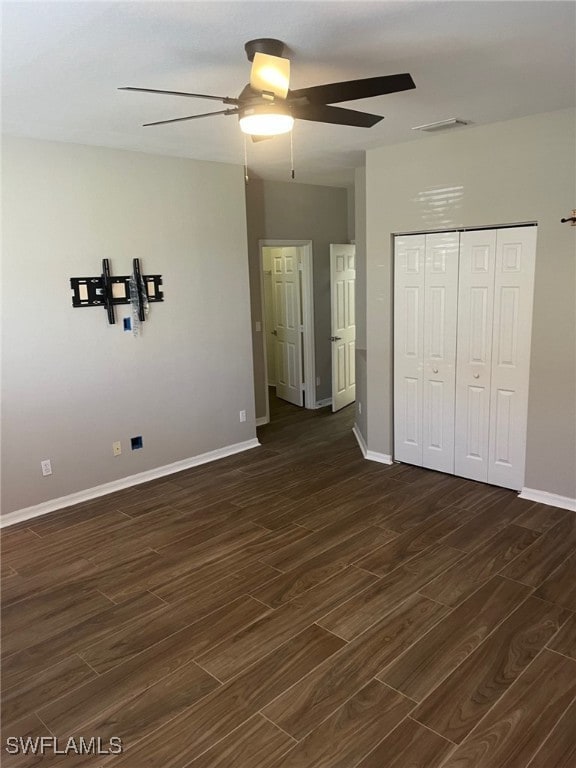 unfurnished bedroom featuring ceiling fan, dark wood-type flooring, and a closet