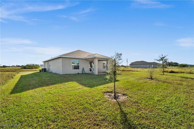 view of front of home with cooling unit, a rural view, and a front yard