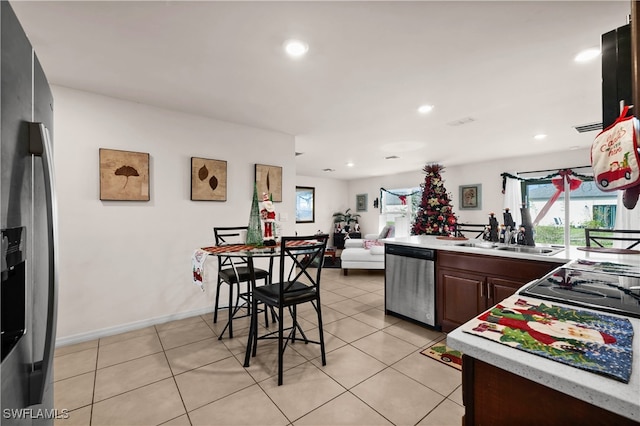 kitchen featuring sink, stainless steel appliances, a breakfast bar, light tile patterned flooring, and dark brown cabinets