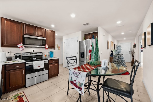 kitchen featuring dark brown cabinetry, light tile patterned floors, and stainless steel appliances