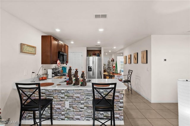 7024 Waldo Cir, Labelle, FL 33935 - kitchen featuring black microwave, stainless steel refrigerator with ice dispenser, a peninsula, a kitchen bar, and range with electric cooktop