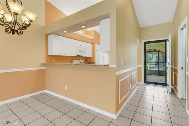 kitchen featuring an inviting chandelier, light tile patterned floors, fridge, decorative light fixtures, and white cabinets