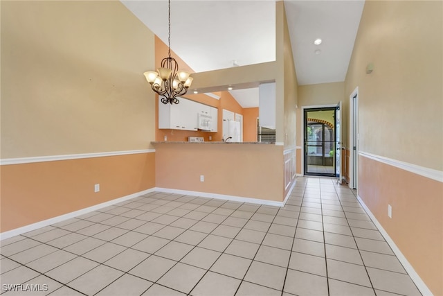 kitchen featuring pendant lighting, lofted ceiling, white cabinetry, kitchen peninsula, and light tile patterned floors