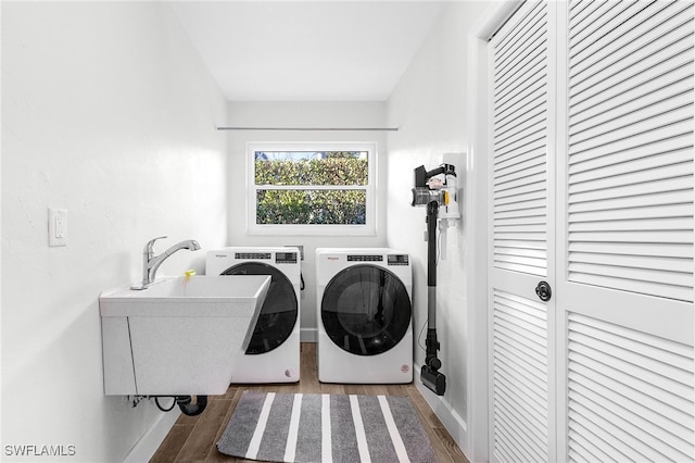 clothes washing area with separate washer and dryer, dark hardwood / wood-style floors, and sink