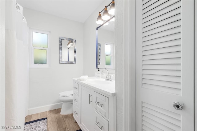 bathroom with a wealth of natural light, hardwood / wood-style floors, vanity, and toilet