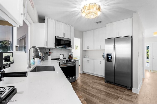 kitchen with light hardwood / wood-style flooring, white cabinets, and appliances with stainless steel finishes