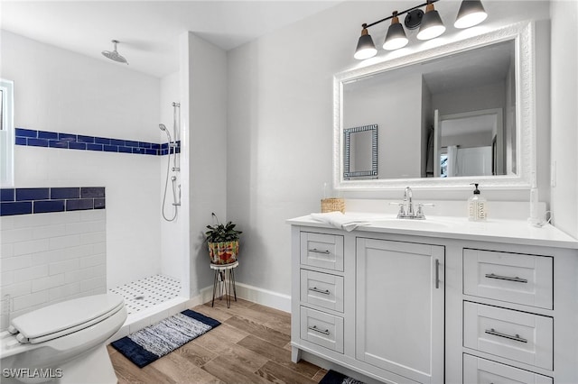 bathroom with a shower, hardwood / wood-style floors, vanity, and toilet