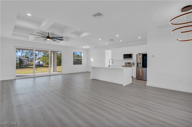 unfurnished living room with beam ceiling, ceiling fan, sink, coffered ceiling, and light hardwood / wood-style flooring