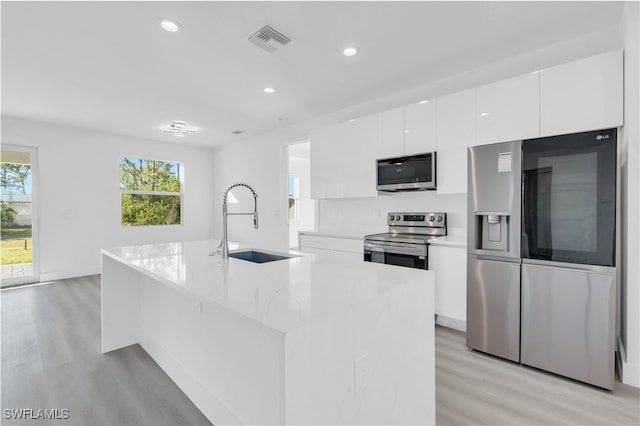 kitchen with plenty of natural light, sink, appliances with stainless steel finishes, and an island with sink