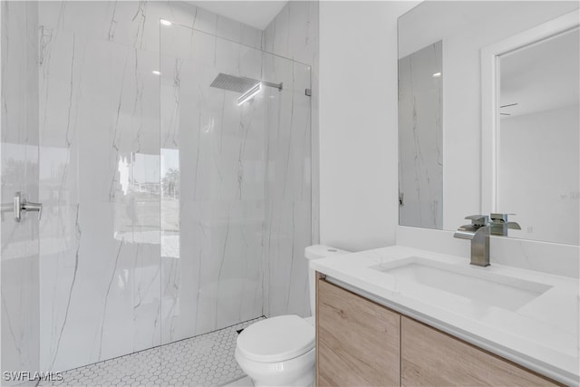 bathroom featuring a tile shower, vanity, and toilet