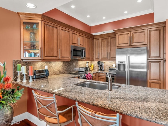 kitchen with light stone counters, appliances with stainless steel finishes, tasteful backsplash, a kitchen bar, and kitchen peninsula