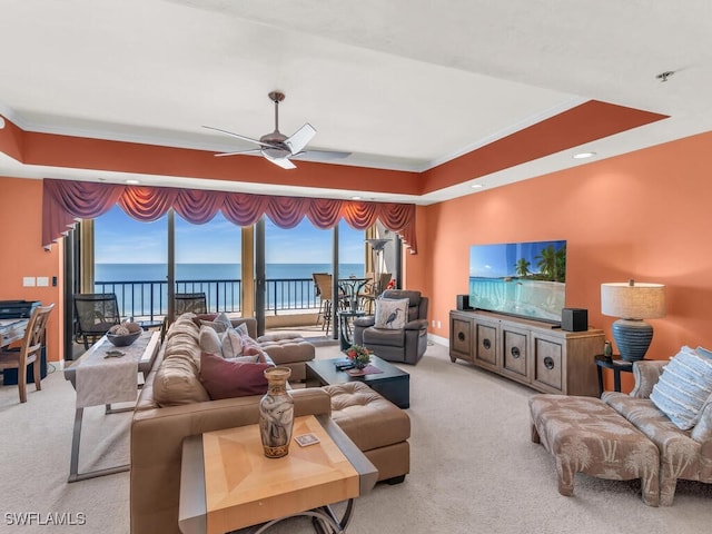 living room with light colored carpet, a raised ceiling, ceiling fan, and ornamental molding