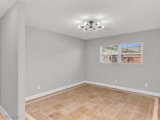 tiled spare room featuring an inviting chandelier