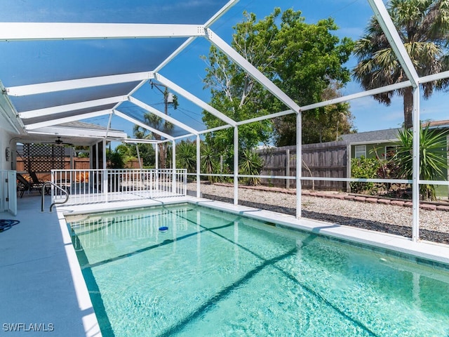 view of pool with glass enclosure, ceiling fan, and a patio area