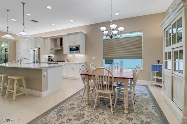 dining room featuring sink, plenty of natural light, light tile patterned flooring, and a notable chandelier