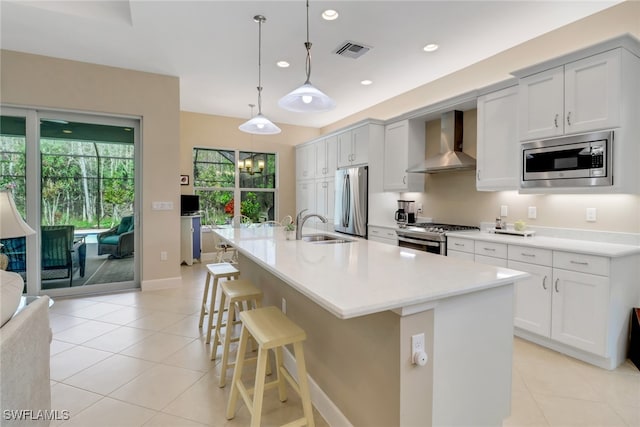 kitchen featuring hanging light fixtures, a breakfast bar area, wall chimney exhaust hood, a large island, and stainless steel appliances