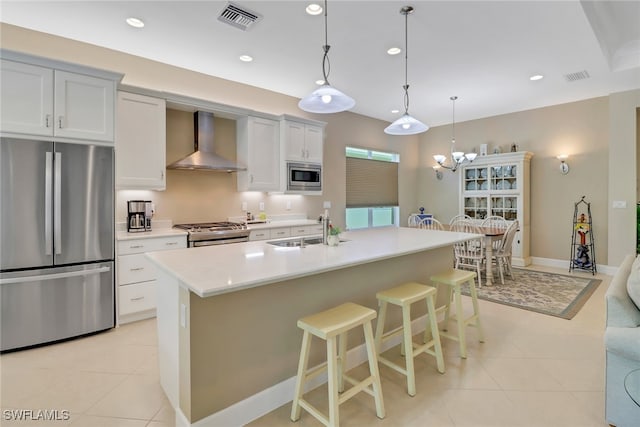 kitchen featuring a center island with sink, sink, wall chimney range hood, and stainless steel appliances