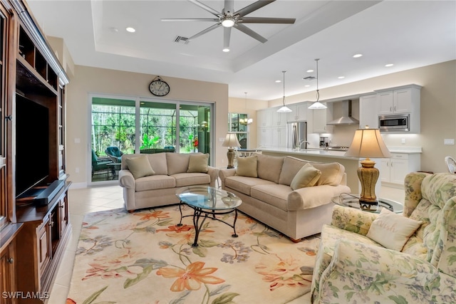 living room featuring ceiling fan, light tile patterned floors, sink, and a tray ceiling