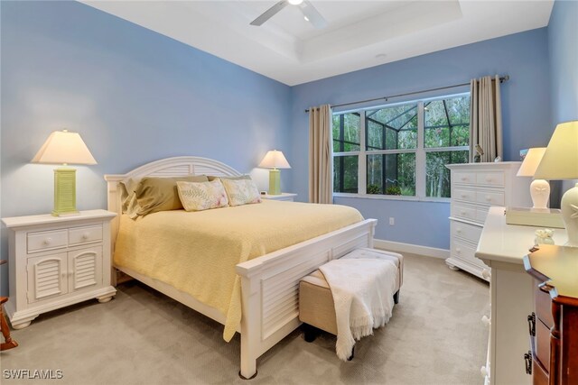 carpeted bedroom featuring a tray ceiling and ceiling fan