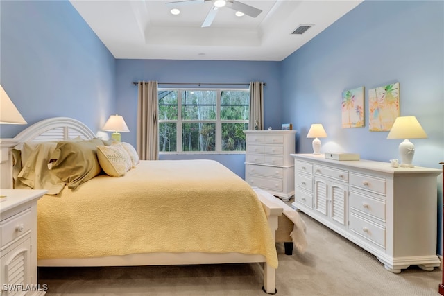 bedroom featuring ceiling fan, light carpet, and a tray ceiling