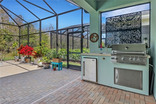 view of patio / terrace with glass enclosure, a grill, and exterior kitchen