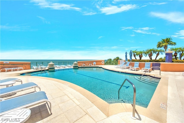 view of swimming pool with a patio and a water view