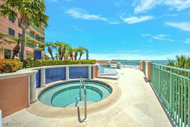 view of pool with a water view and a hot tub