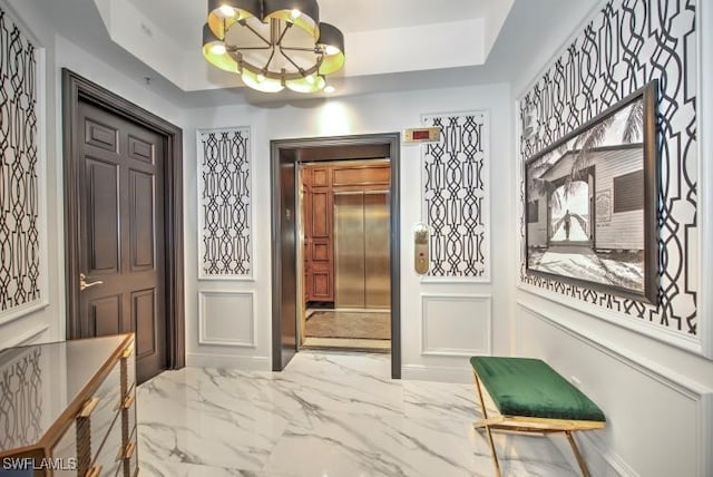 interior space with a notable chandelier, elevator, and a tray ceiling