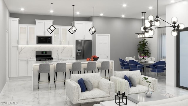 kitchen with stainless steel fridge, white cabinetry, black microwave, and a kitchen island with sink