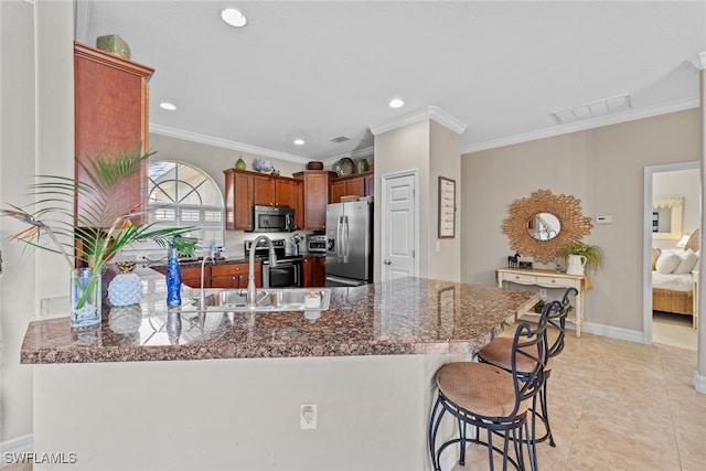 kitchen with kitchen peninsula, ornamental molding, stainless steel appliances, and a breakfast bar area