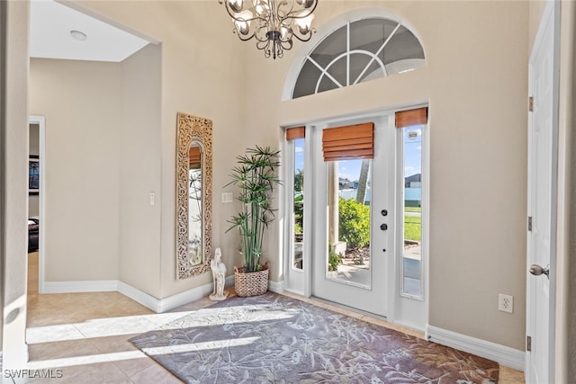 tiled entrance foyer featuring a high ceiling and a notable chandelier