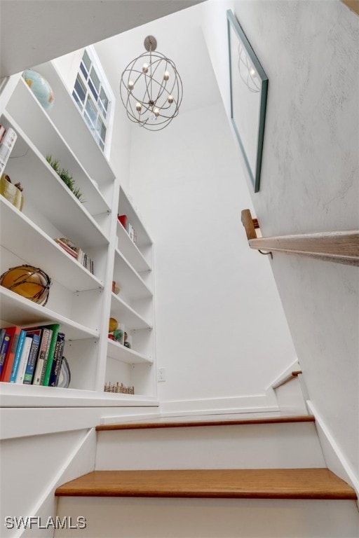 stairs featuring a notable chandelier