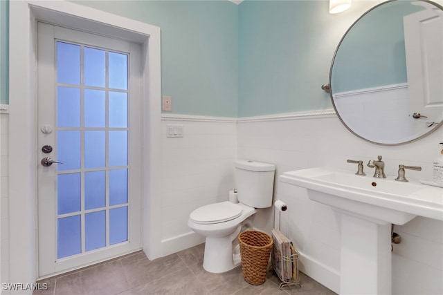 bathroom featuring tile patterned flooring, sink, toilet, and tile walls