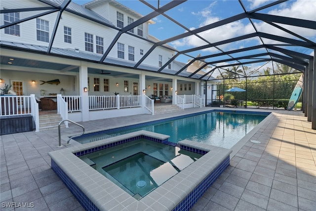 view of pool featuring glass enclosure, an in ground hot tub, and a patio